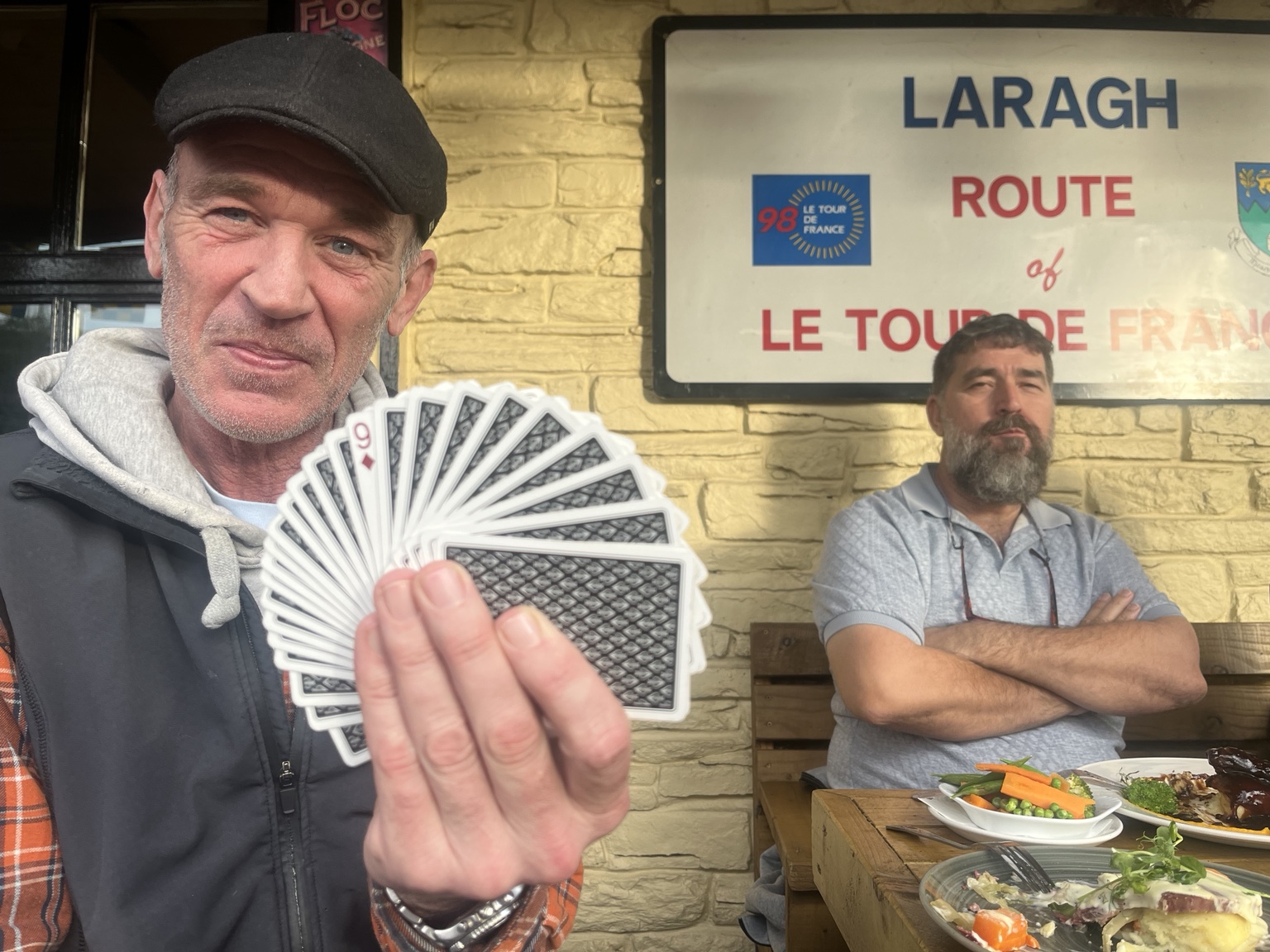 Barry in his flat cap holding a fan of playing cards at Lynhams